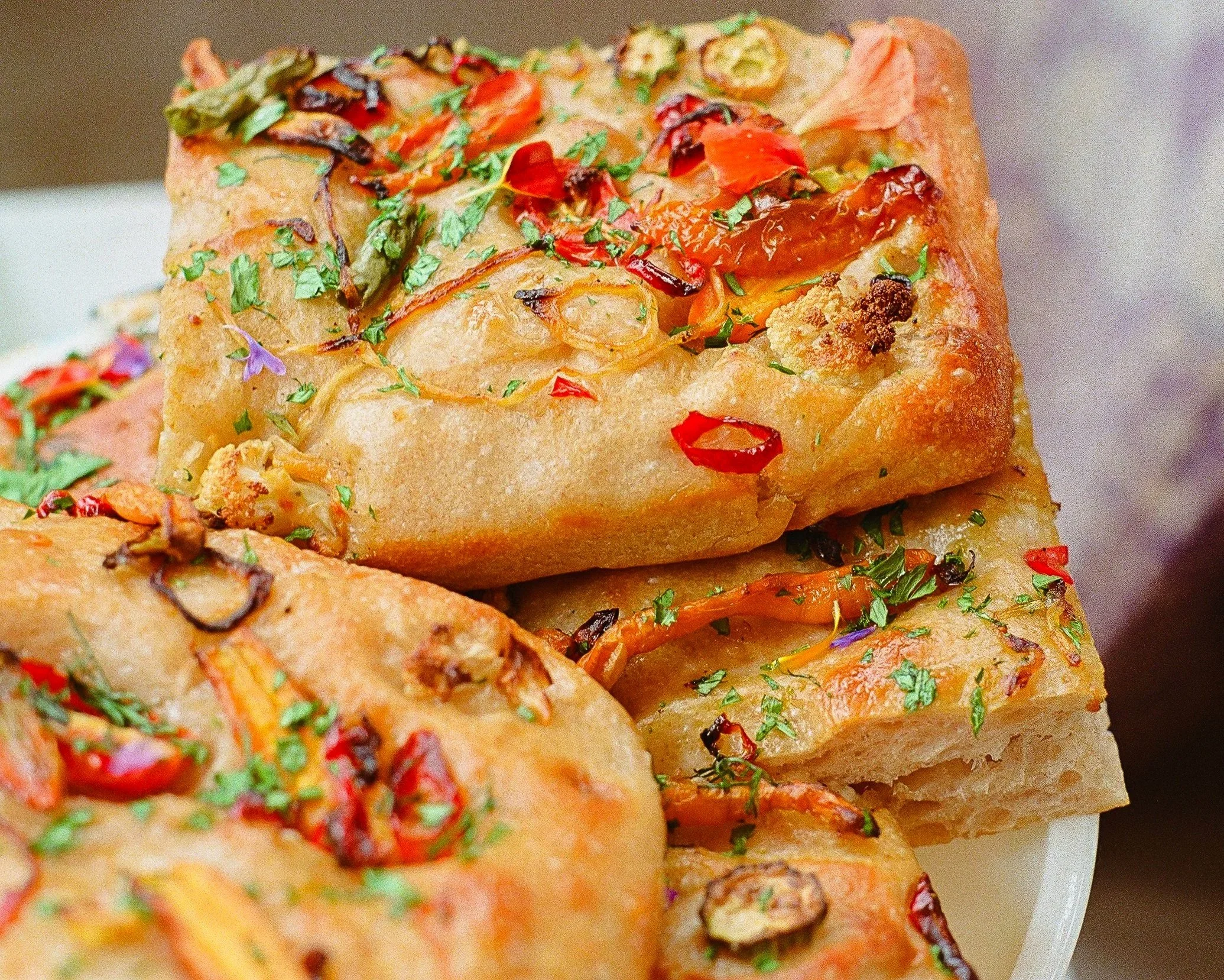 A close up image of the "Taste of the Market" Focaccia, which is covered in colorful seasonal produce and edible flowers