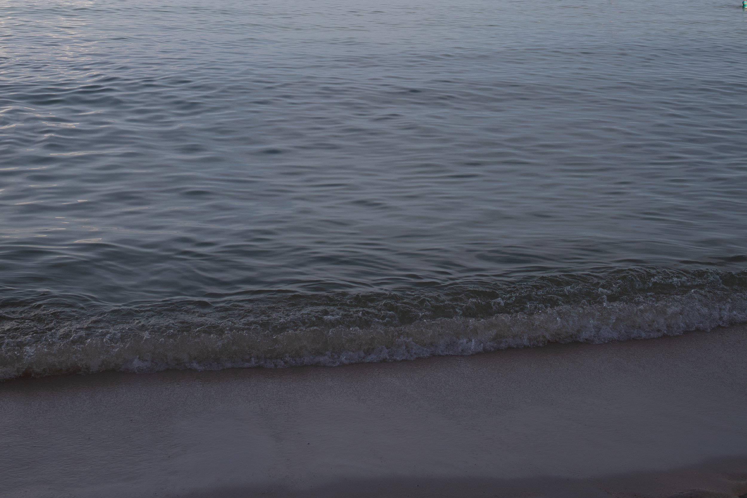 Calm ocean waves gently lapping against a sandy beach.