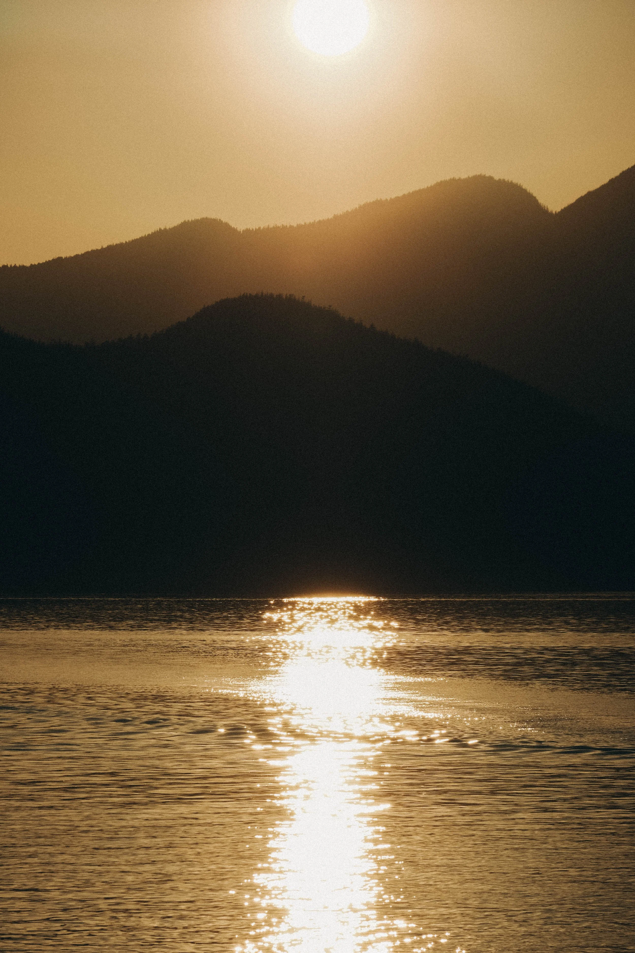 Sunset over mountains reflected on a body of water.