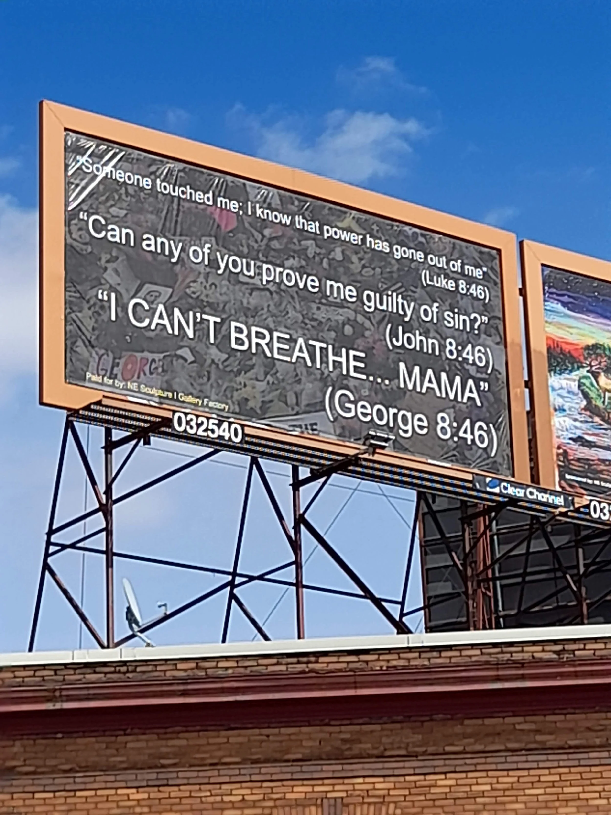 Billboard displaying a religious quote from the Bible, John 8:46, with black background and white text. The quote discusses Jesus and being accused of sin. The billboard is mounted on a metal structure with part of a brick building visible at the bot