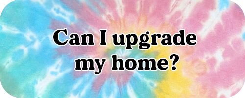 Colorful tie-dye background with bold text reading ‘Can I upgrade my home?’ used as a navigation button for a homeowner decision tool on Jeanette Corbin’s Mid Michigan real estate website.