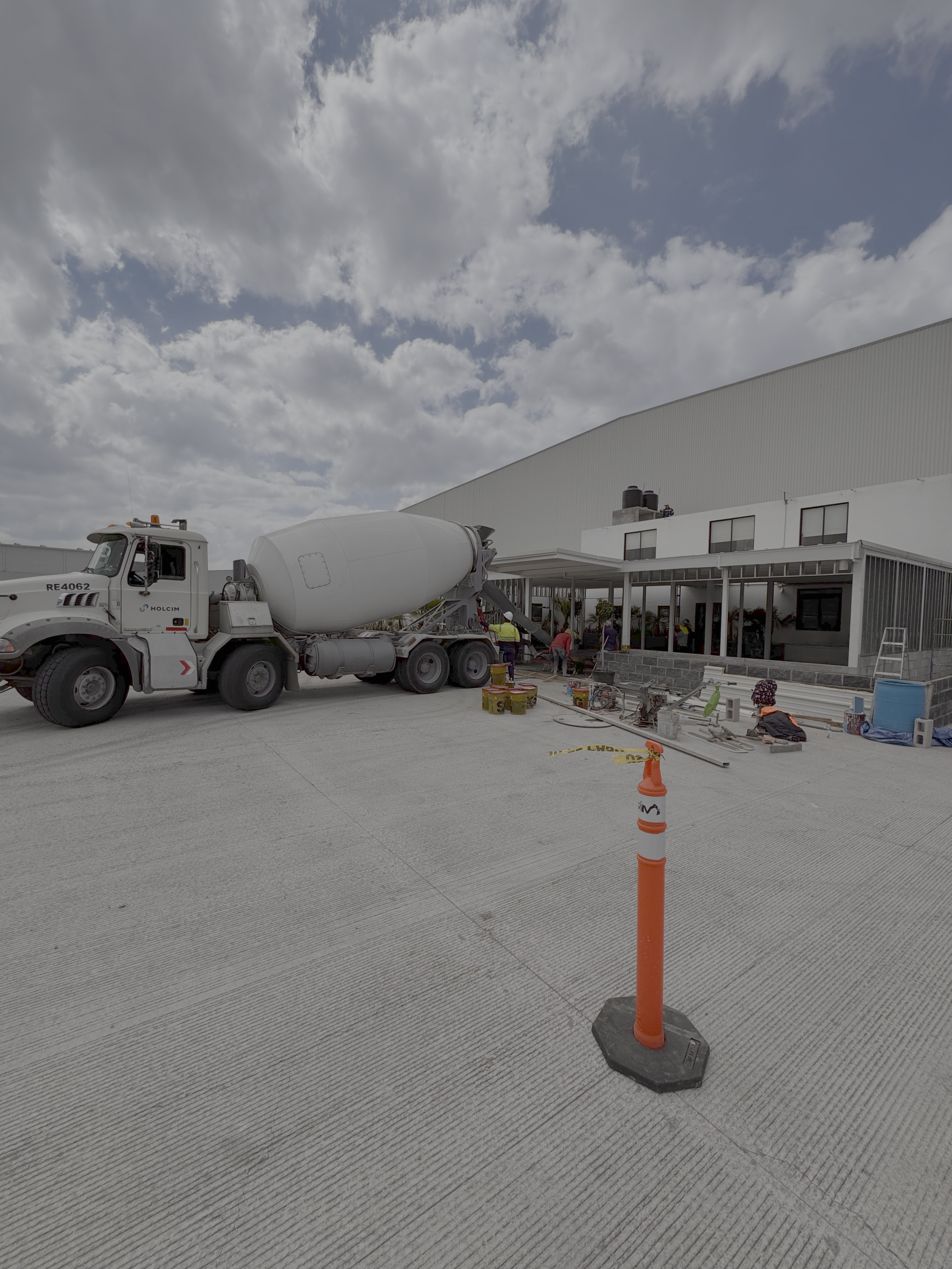 Construcción en progreso en un edificio con una excavadora y empleados trabajando.