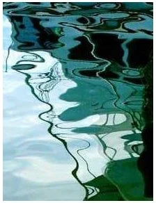 Abstract reflection of trees and sky on water with ripples.