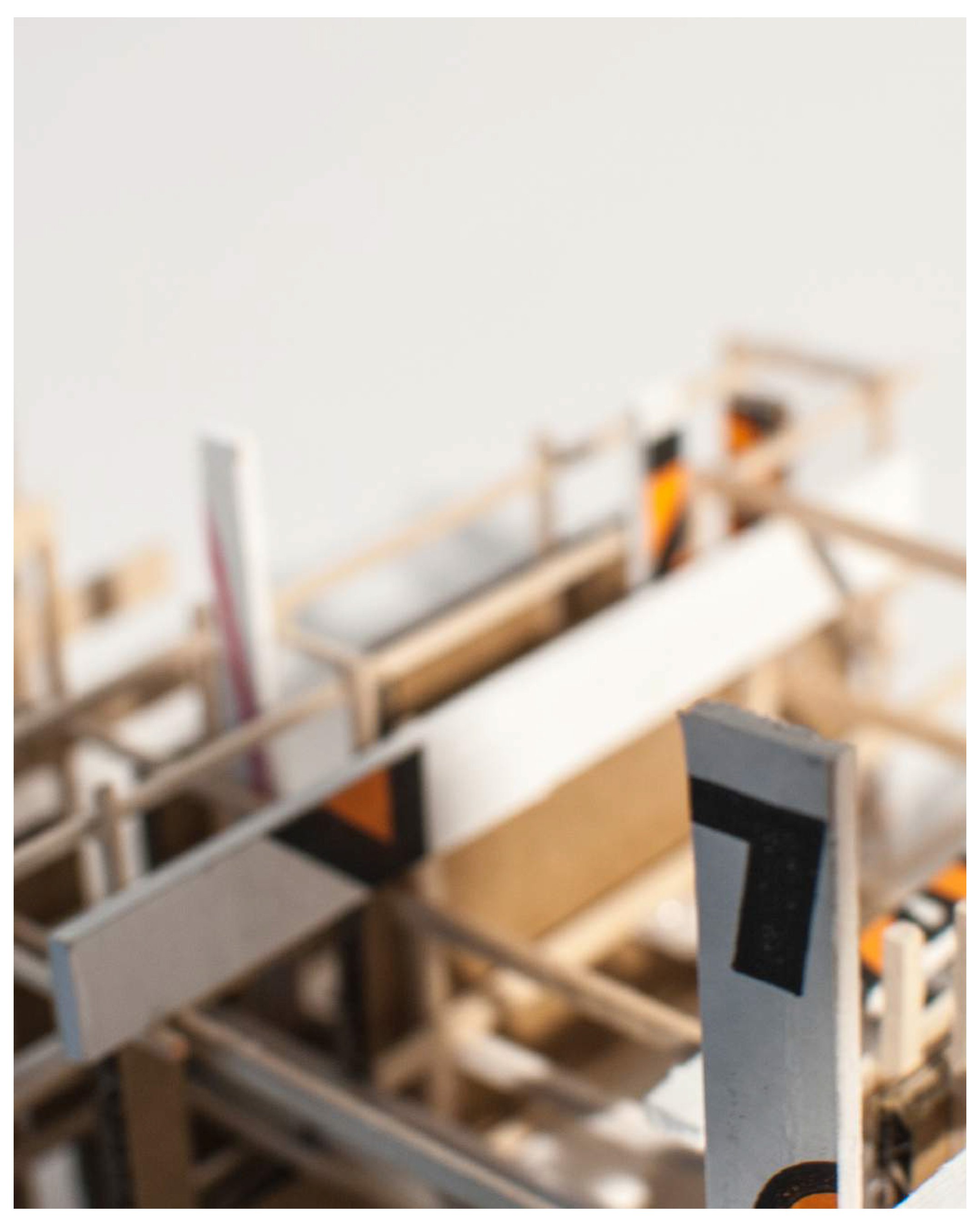 Close-up of a miniature wooden architectural model with painted black, orange, and white details.