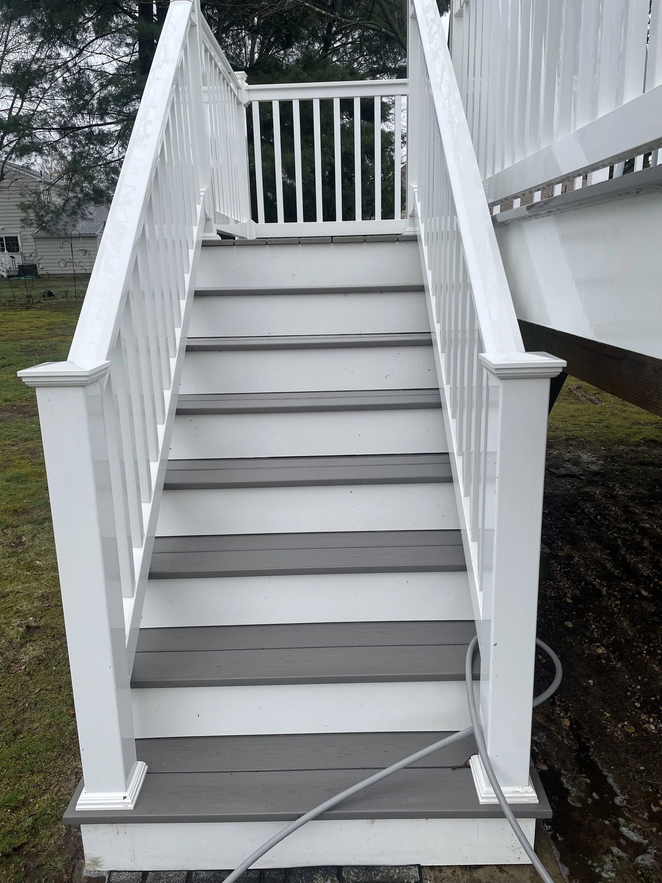 Outdoor white staircase with railings leading up to a deck.