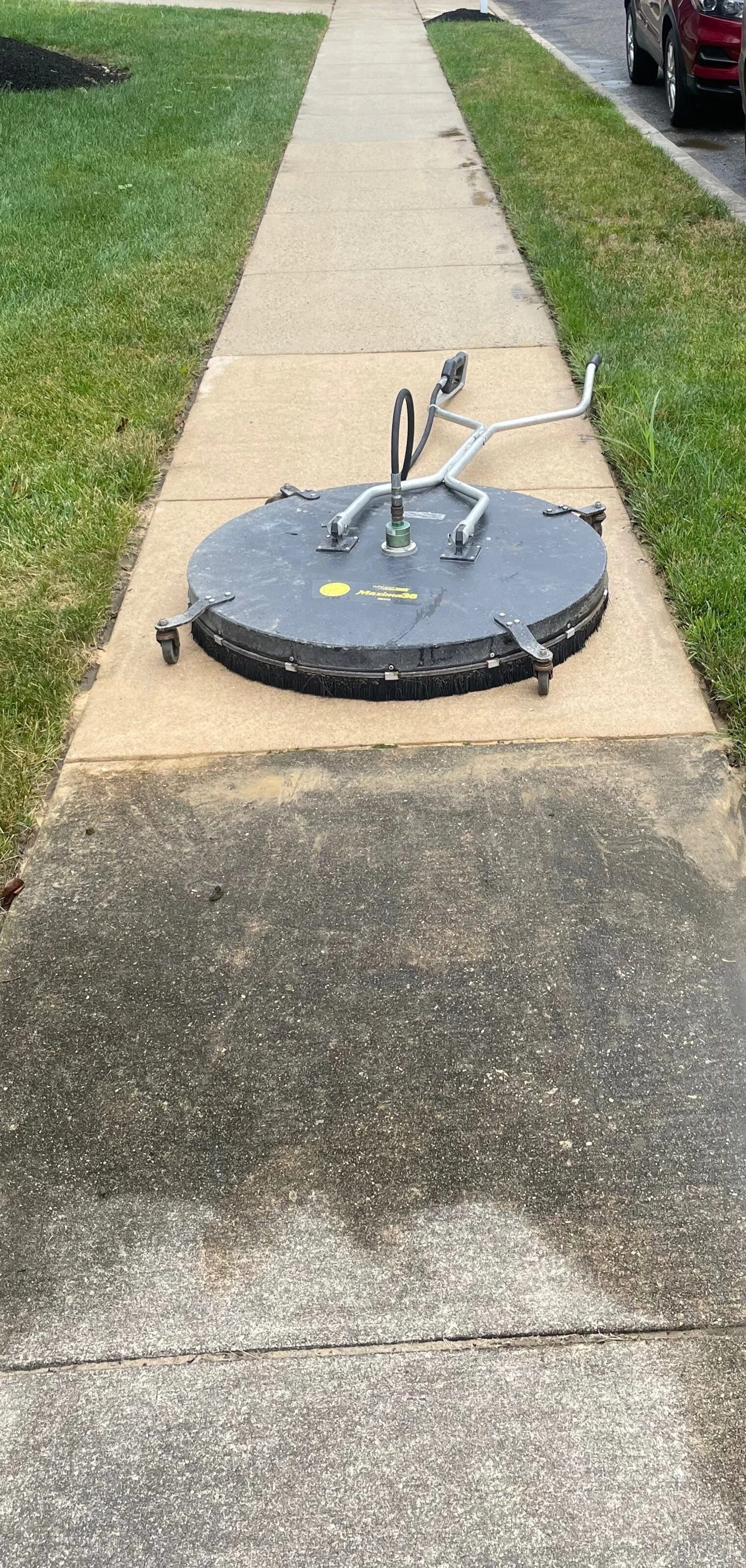 A sidewalk power trowel machine parked on the sidewalk.
