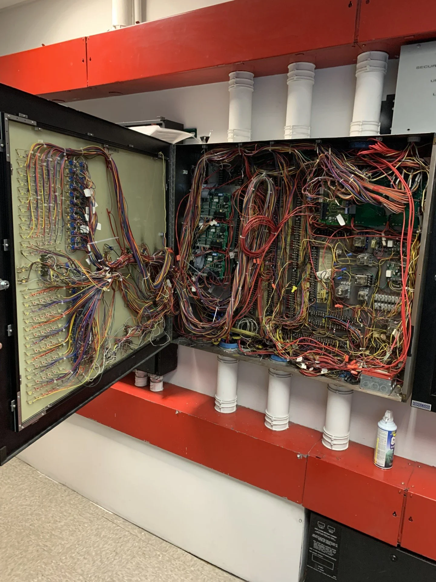 Open control panel with numerous tangled wires and electronic circuit boards inside.