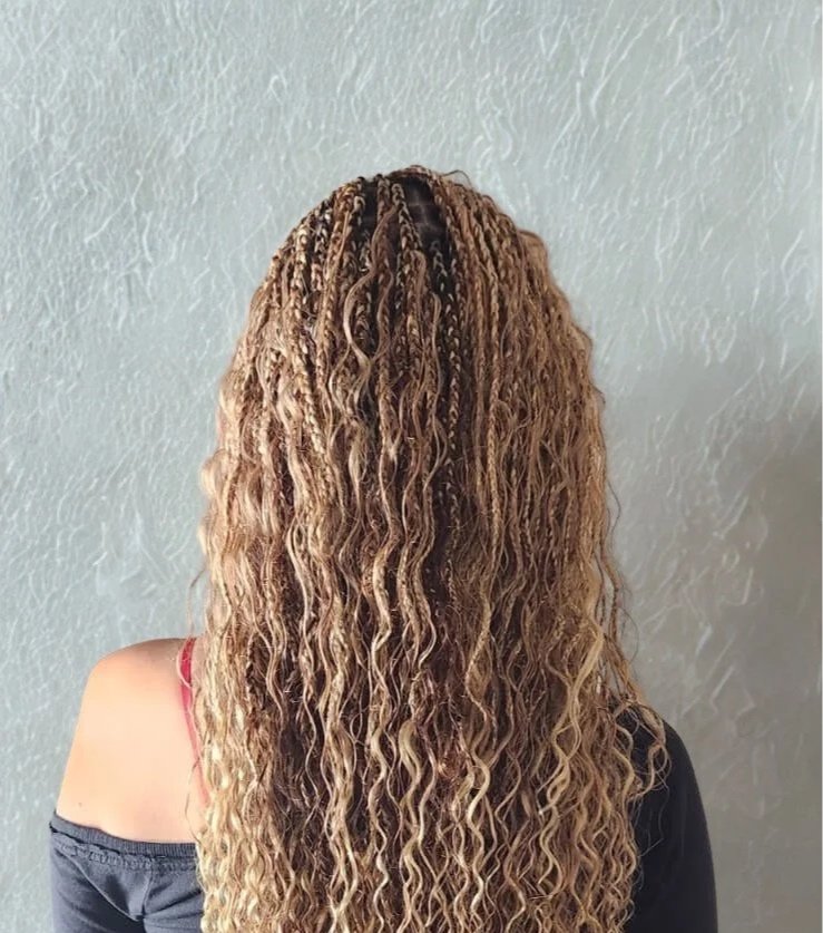 Back of a person's head with long, curly, light brown hair styled in small braids and loose curls.