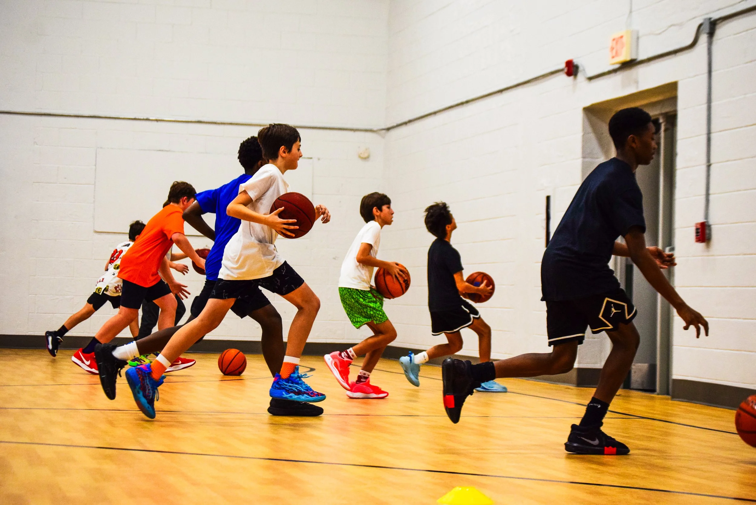 Young boys practicing basketball drills in an indoor gym.