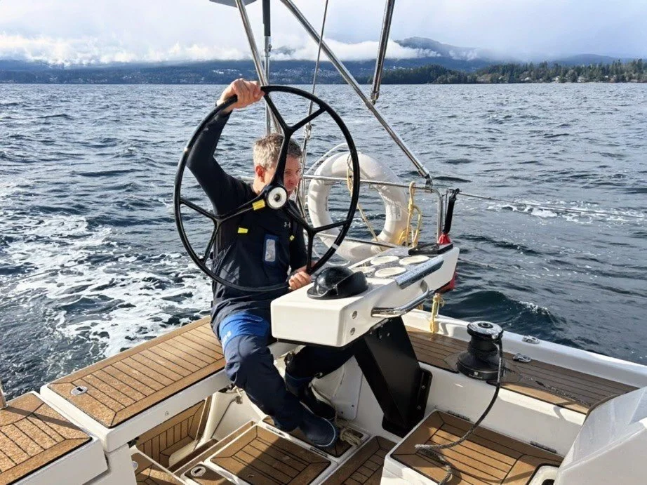A person sailing a boat on a body of water with mountains in the background.