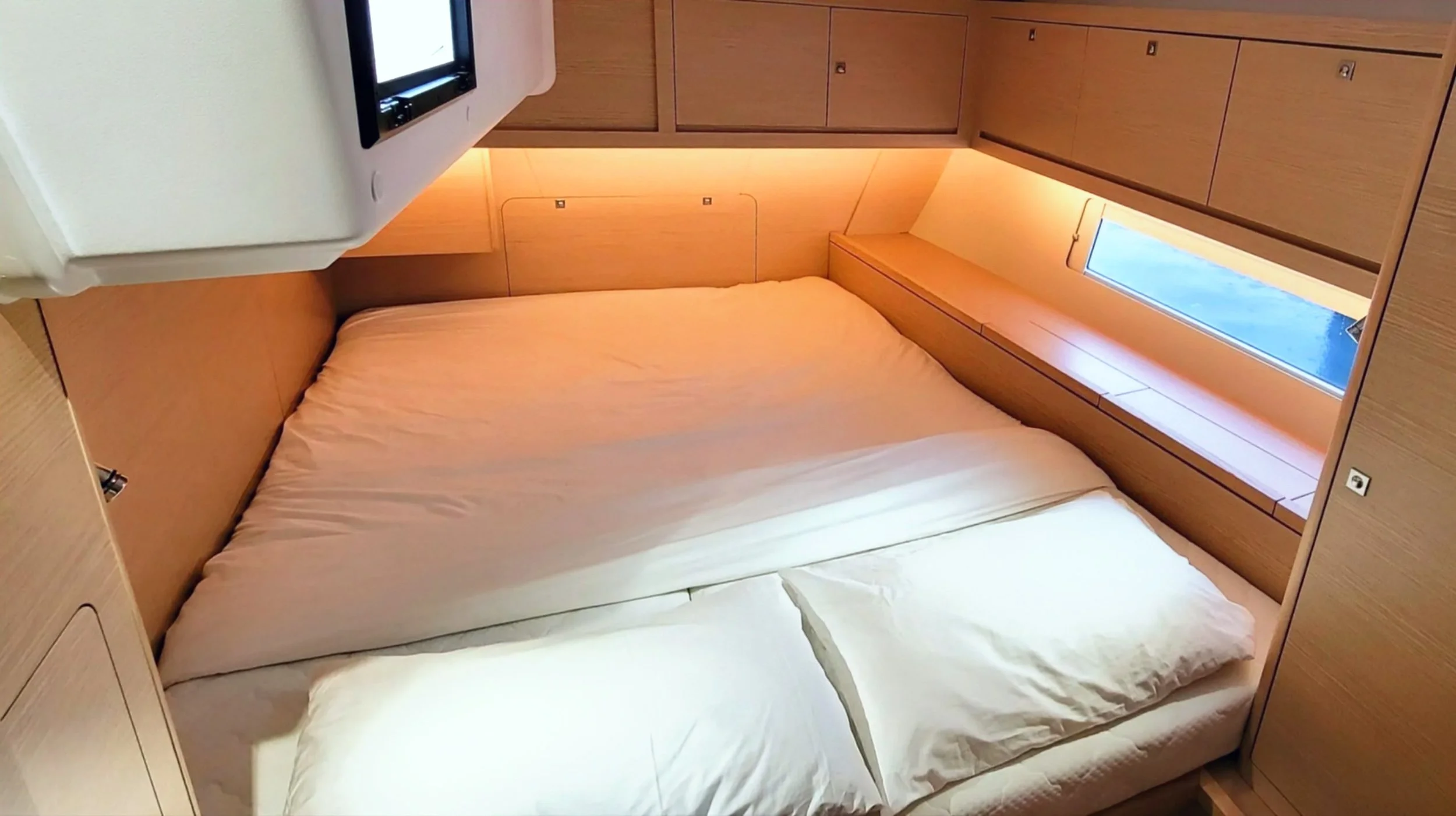 A cozy bedroom in a wooden cabin with a large bed, soft pillows, and a window with a view, illuminated by warm lighting.