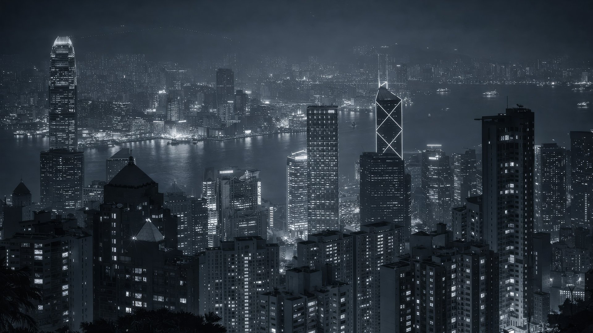 Nighttime aerial view of a city skyline with skyscrapers and a river, illuminated by city lights.
