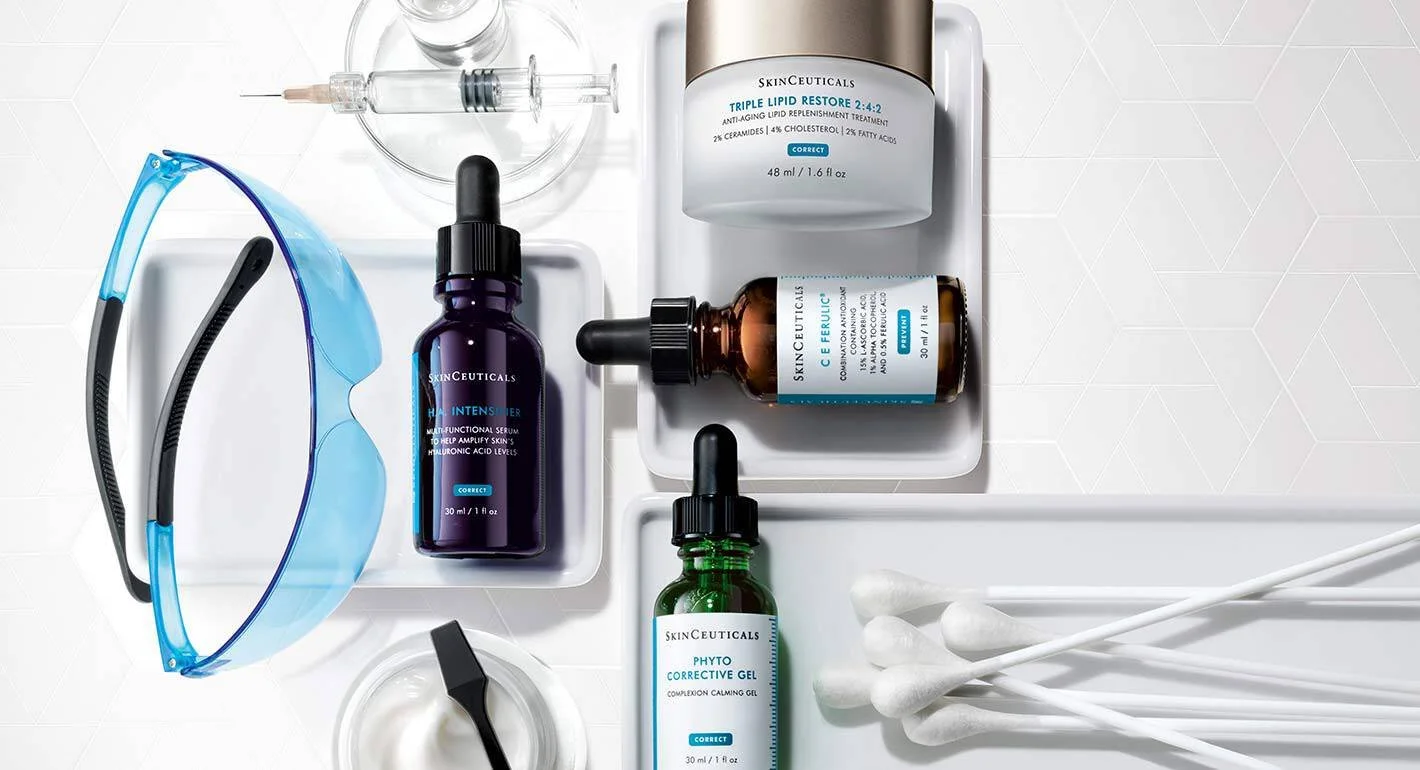 Skincare products, including serums and gels, skincare tools, and cotton swabs, arranged on a white surface.