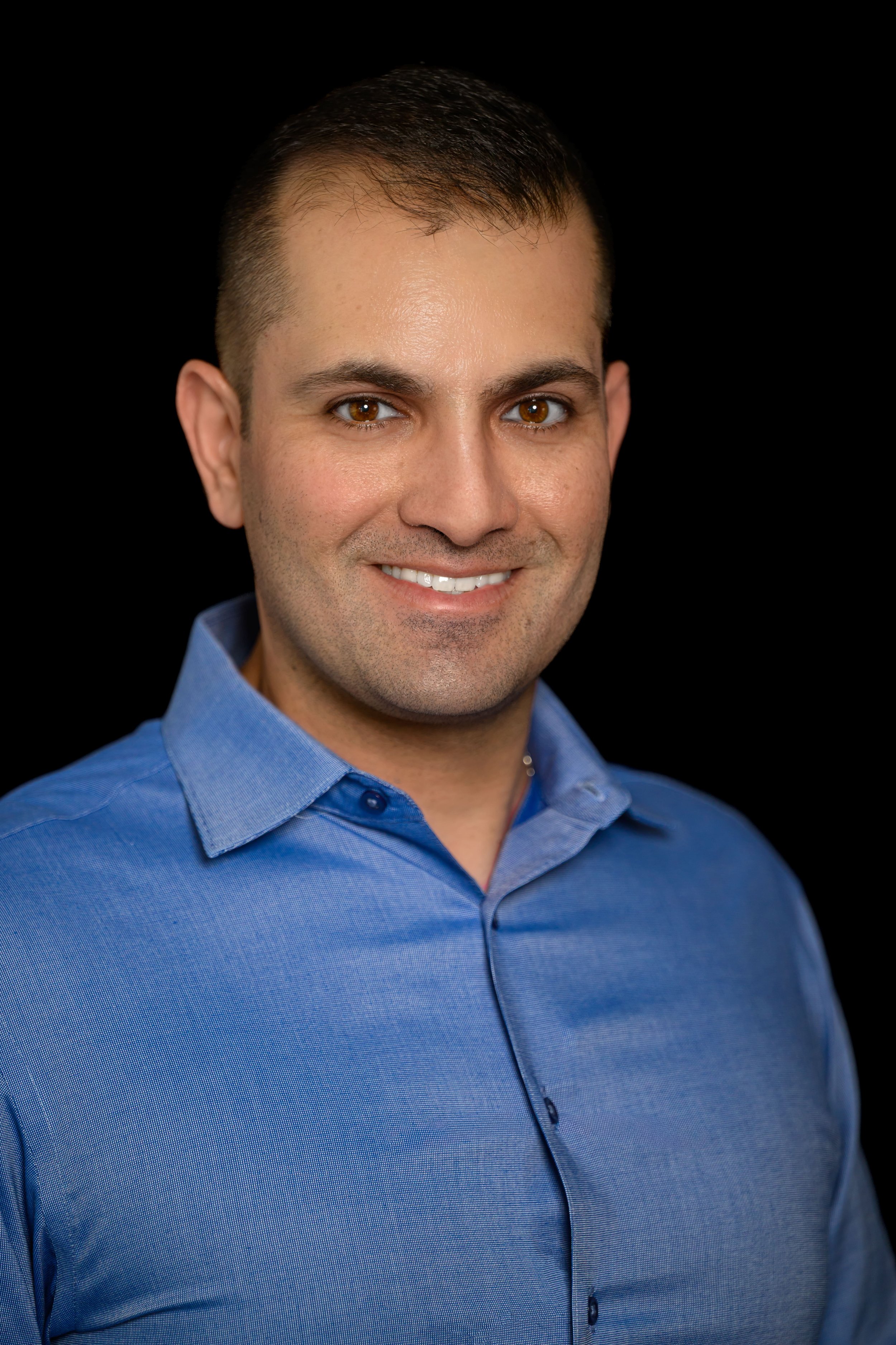 Dr. Said Awad wearing a blue collared shirt against a black background.