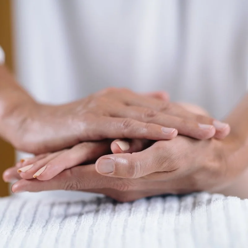 A pair of hands gently holding one hand in between