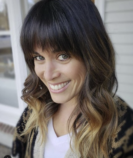 A woman with shoulder-length dark brown hair and blonde ombre ends smiling at the camera.