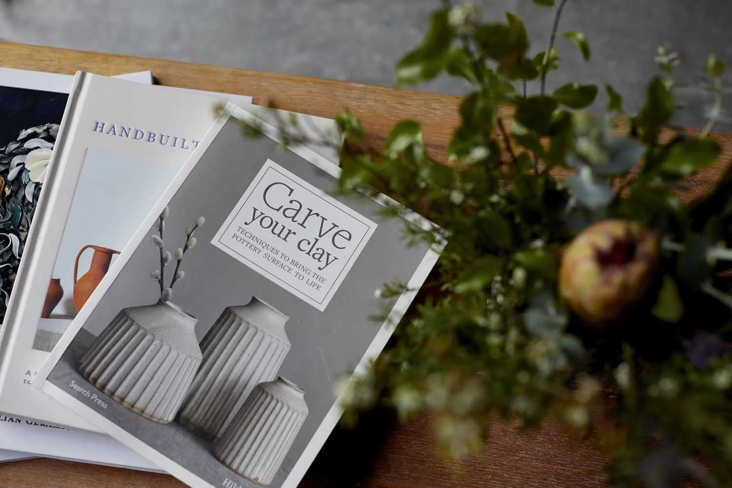 Blurred image of flowers in a vase and the corner of a pottery book