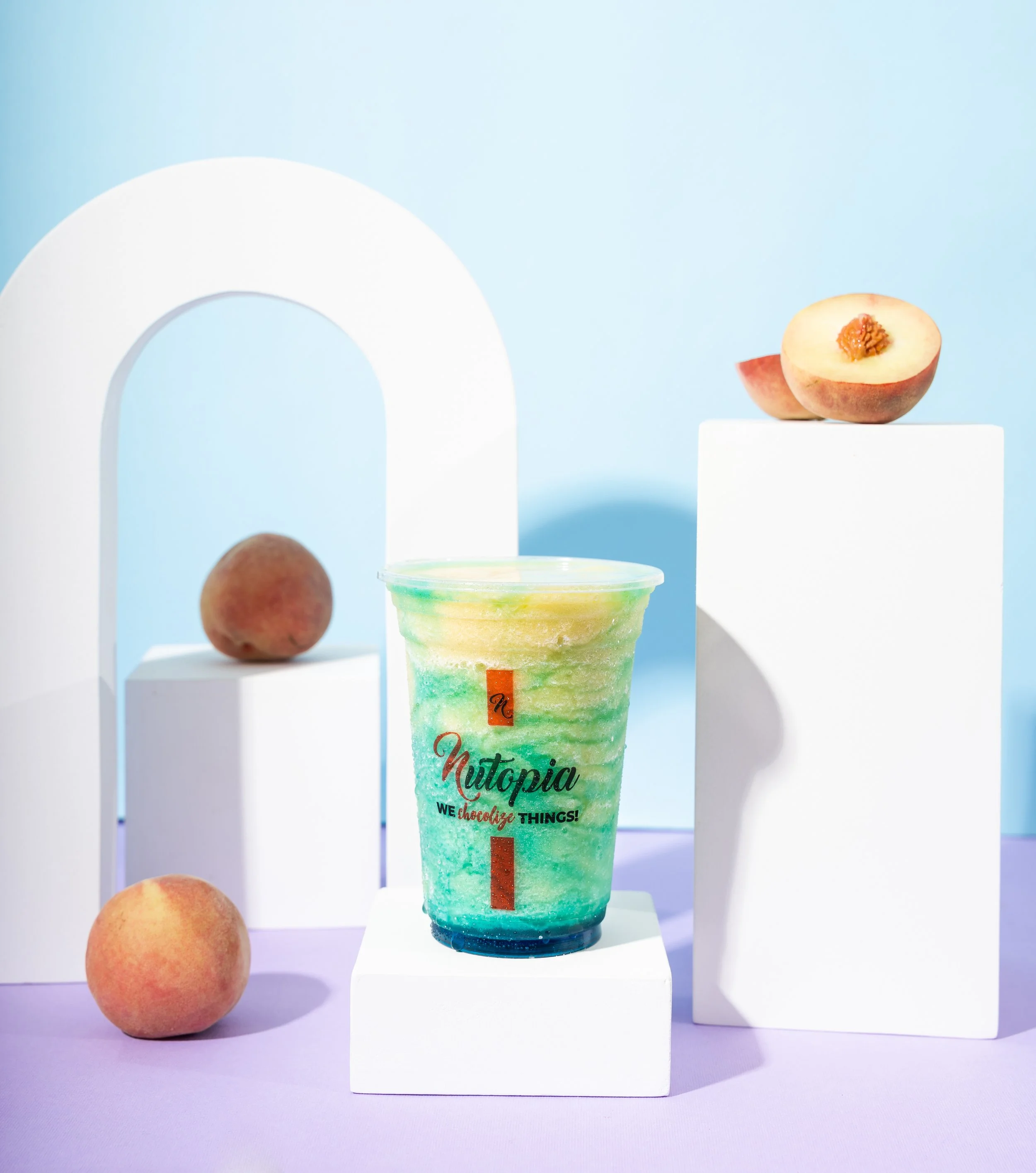 Colorful Nutopia beverage with peaches and decorative white blocks on pastel background.