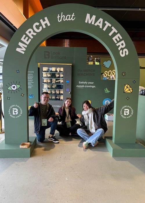 Three marketing team members posing next to the activation they designed at State of Social