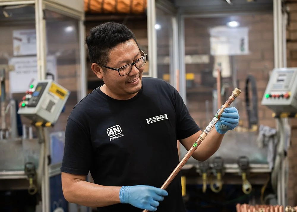 Happy 4N employee inspecting copper pipes