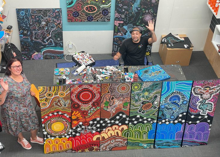 Birds eye view of two Mardaa employees next to a set of completed indigenous artwork