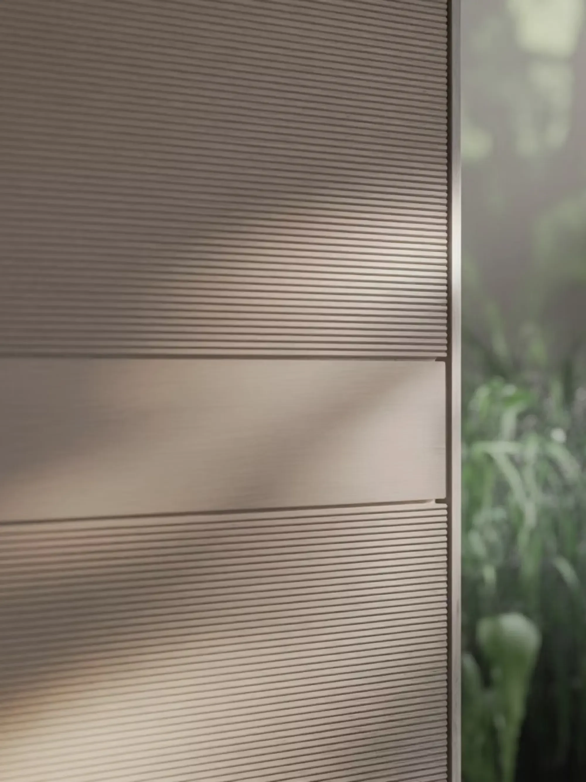 Close-up of a metallic surface with horizontal ridges next to a window with a blurred outdoor view.