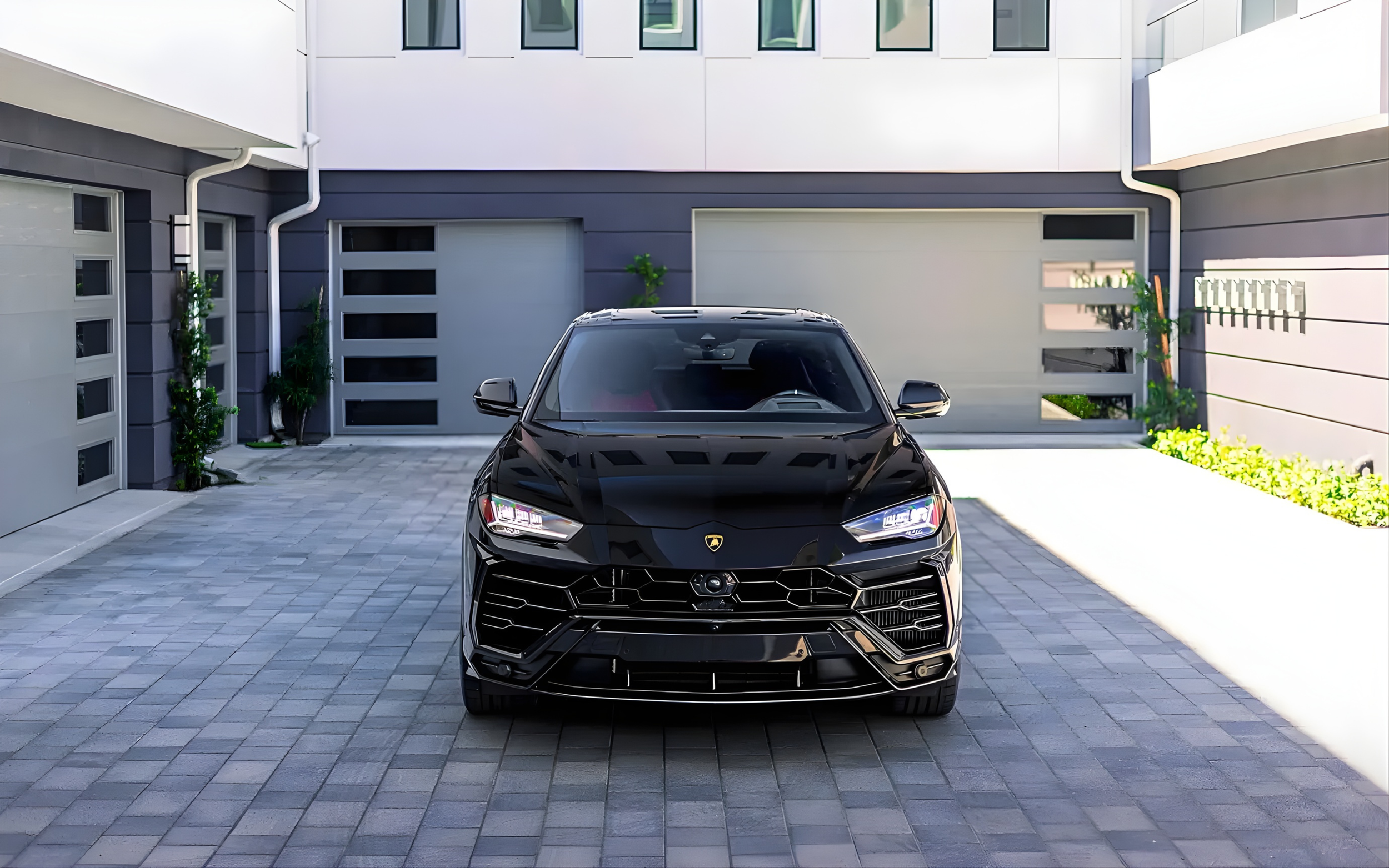 Front view of a black Lamborghini Urus parked in a modern residential driveway.