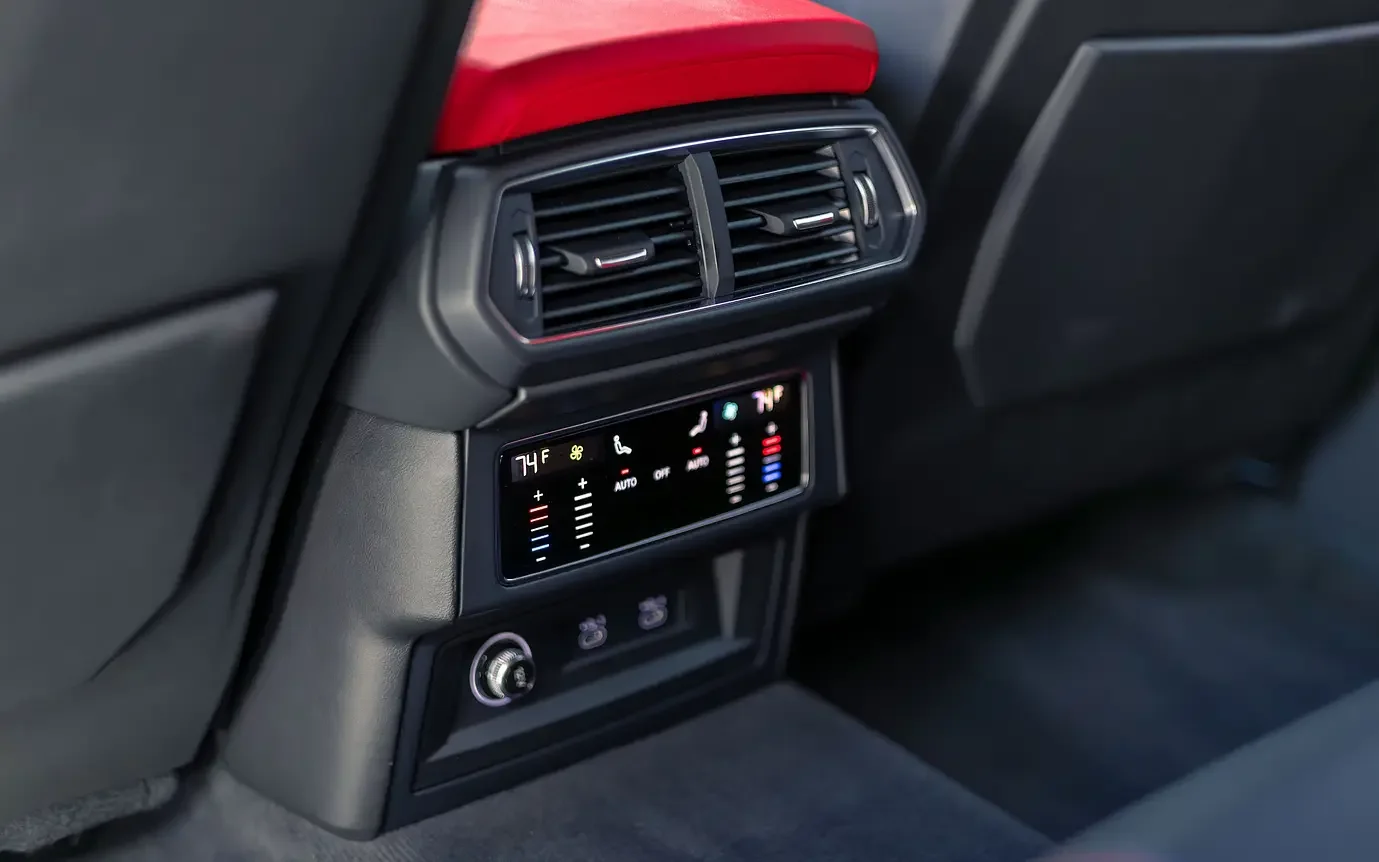 Close-up of the rear center console of a car showing air conditioning vents and digital climate controls showing 74°F and 71°F with fan and temperature adjustment icons.