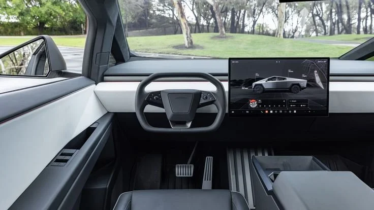 Sleek interior of a Tesla Cybertruck featuring a minimalist steering wheel and a central touchscreen displaying vehicle graphics.