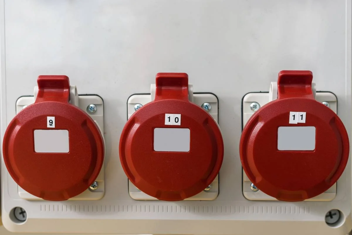 Three red industrial power sockets labeled 9, 10, and 11, mounted on a white panel.