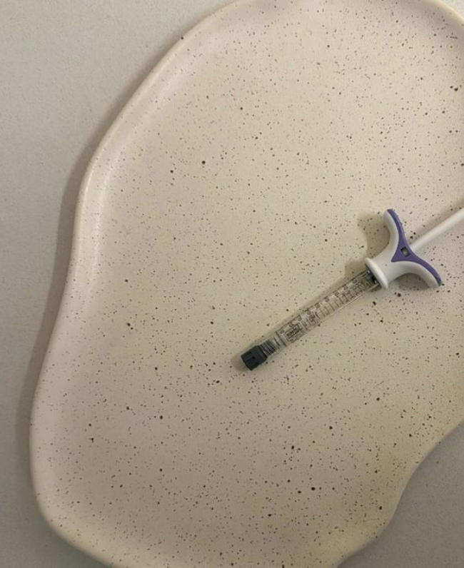 A white speckled cutting board with a syringe placed on it.