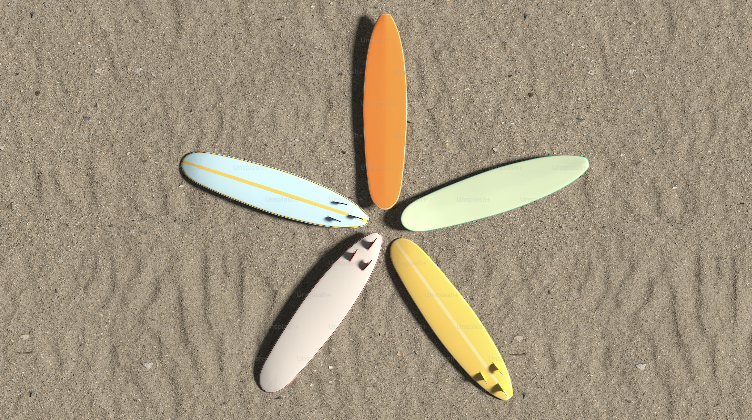 Six colorful surfboards arranged in a flower shape on sandy beach