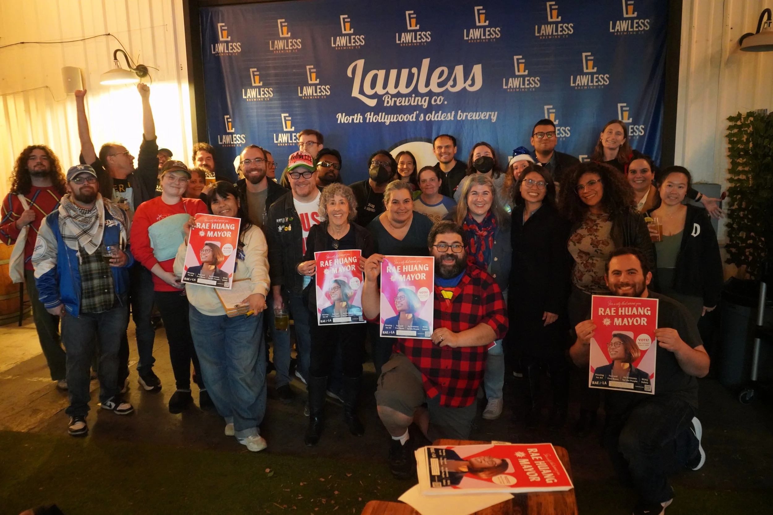 Group of people holding up Rae for LA posters