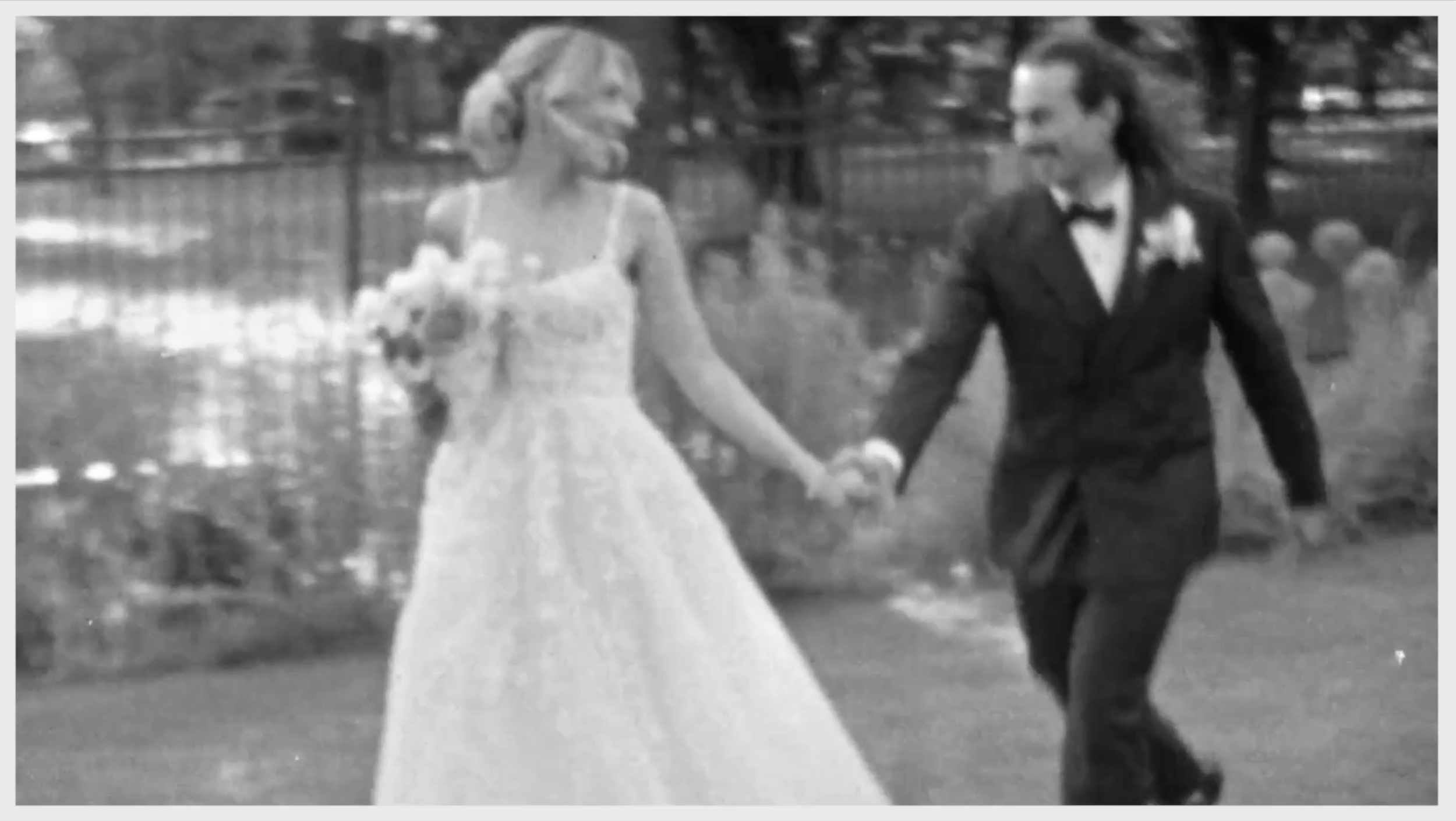 A black and white photo of a bride and groom running. The bride is wearing a white wedding dress and holding a bouquet, and the groom is in a black tuxedo with a bow tie. They are holding hands, and there are trees in the background.