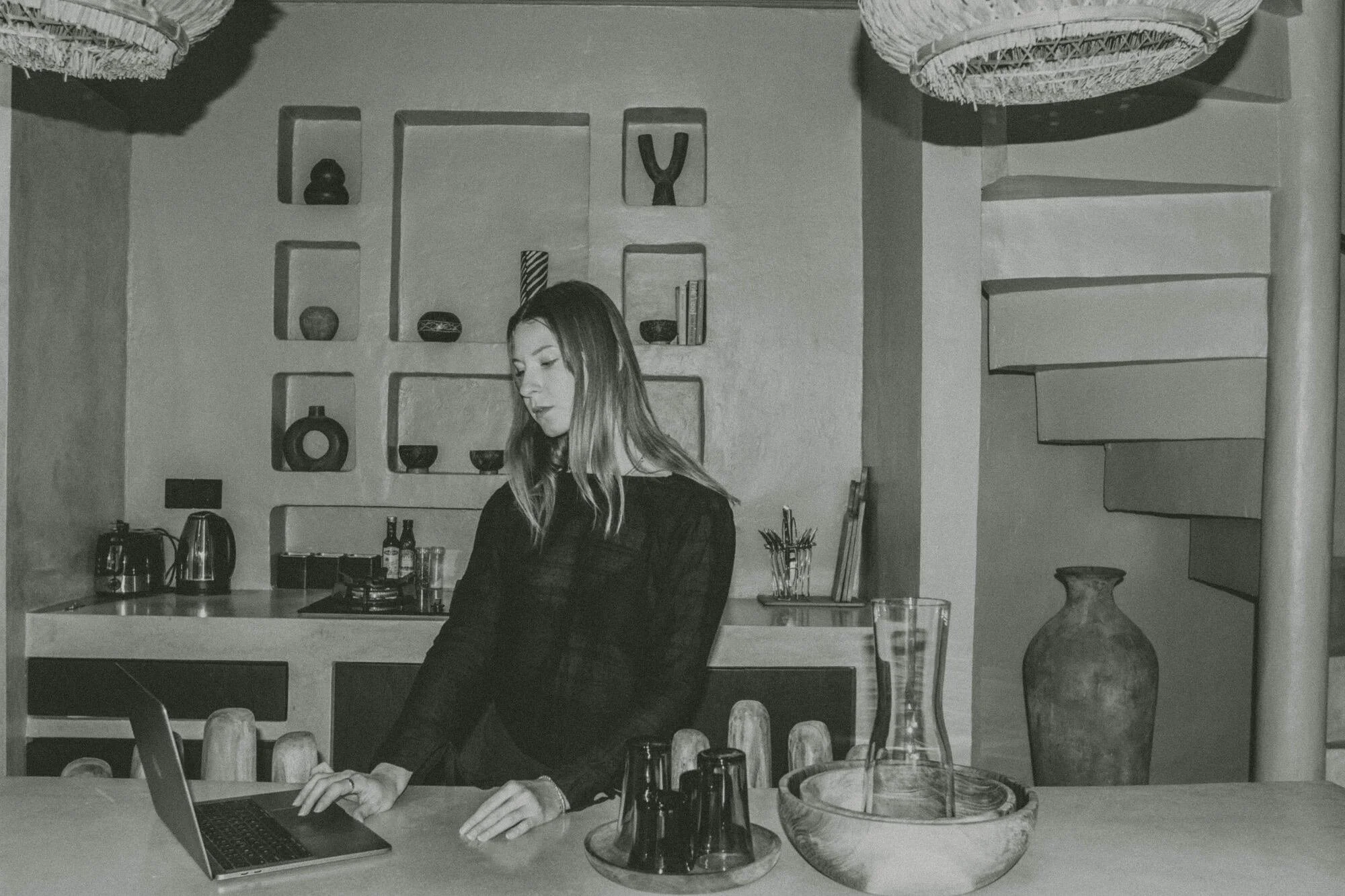 Emily, designer at Will Travel for Disco, standing at a kitchen counter using a laptop.