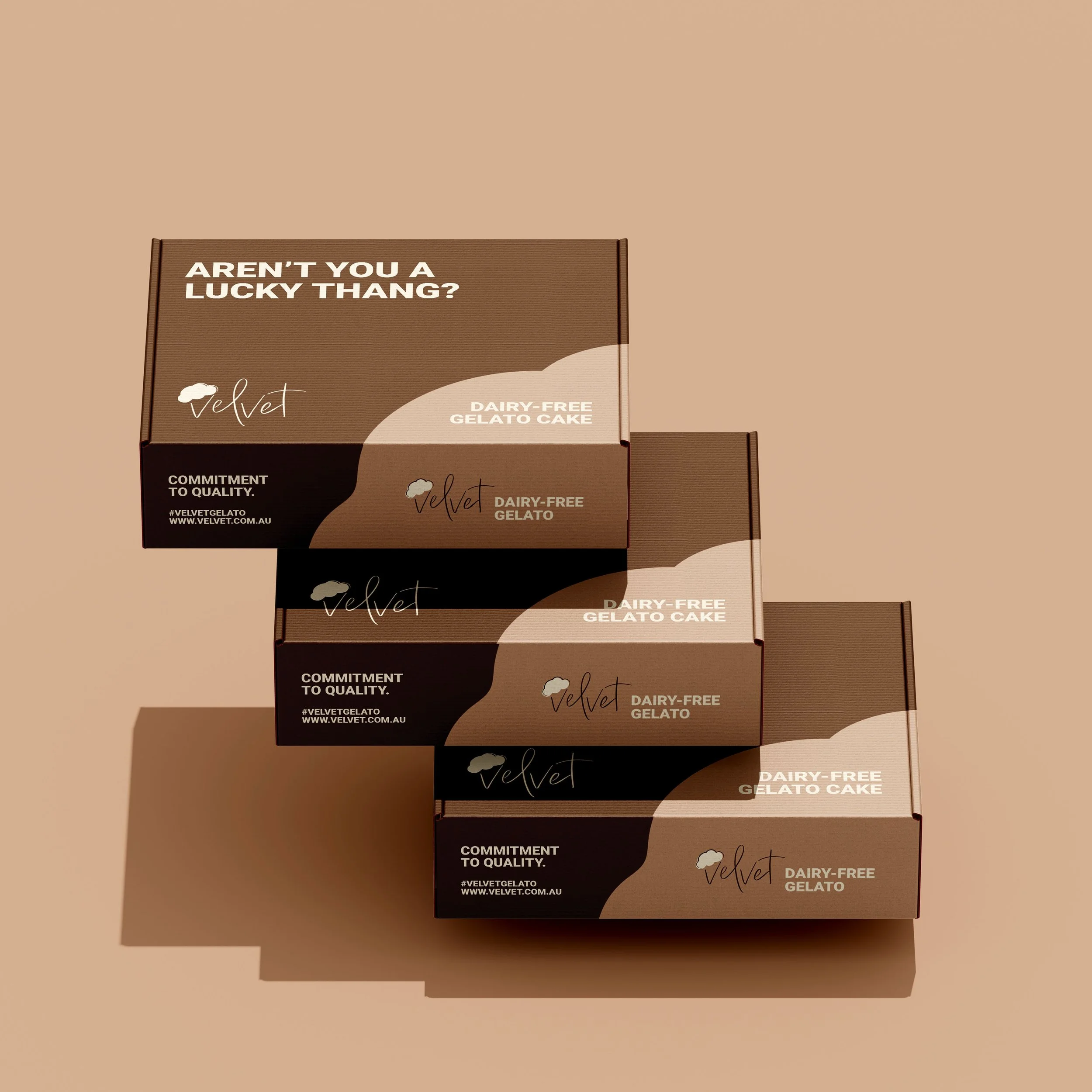 Three stacked boxes of Velvet dairy-free gelato cake on a beige background, with shadow cast on the left side.