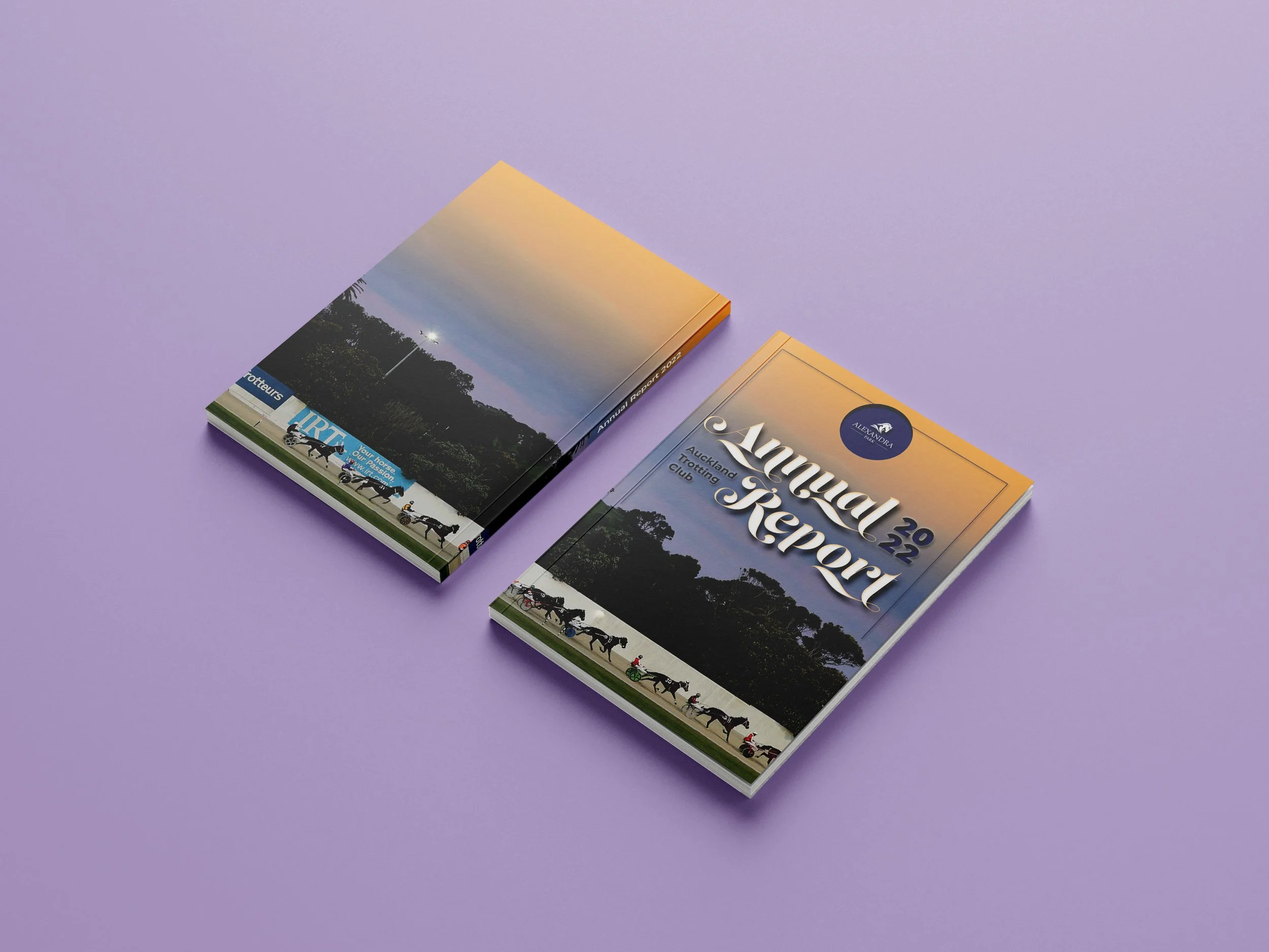 Two stacked booklets featuring a racetrack scene with horses and jockeys on the cover, placed on a purple surface.