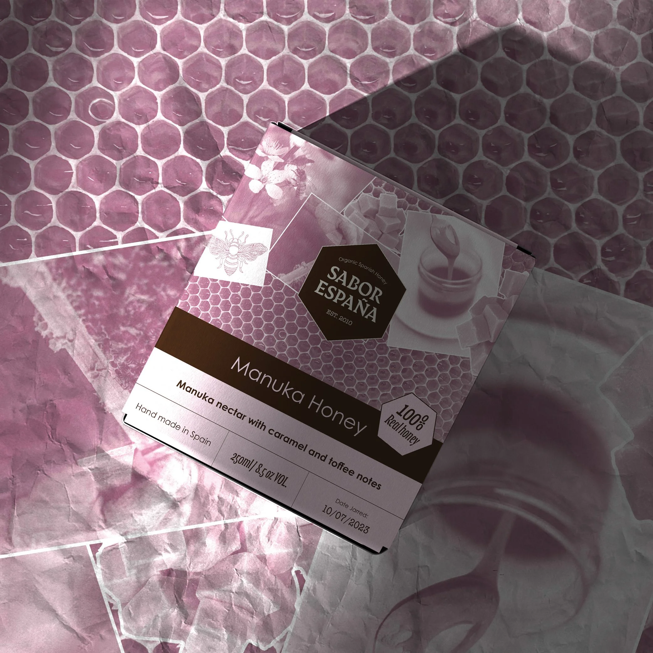 A box of Manuka honey from Sabor España placed on pink honeycomb-patterned wrapping paper.