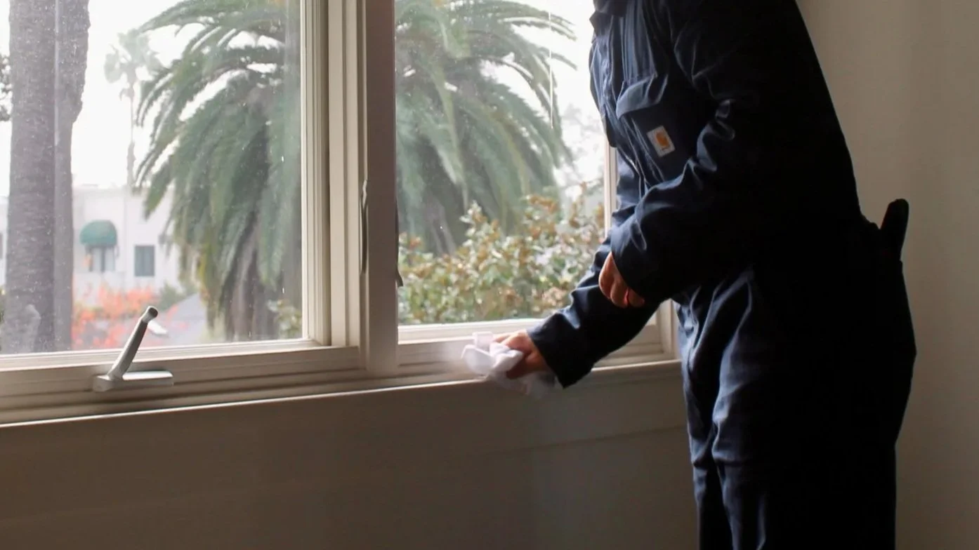 Beachfront houses on stilts with ocean waves, clear sky, and a sandy shore, during sunset or sunrise.