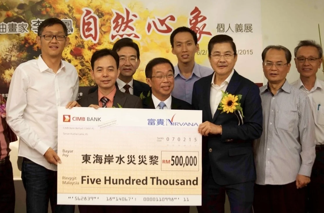 Group of eight men standing together holding a large ceremonial check for RM 500,000 during a donation event, with a colorful banner in the background.
