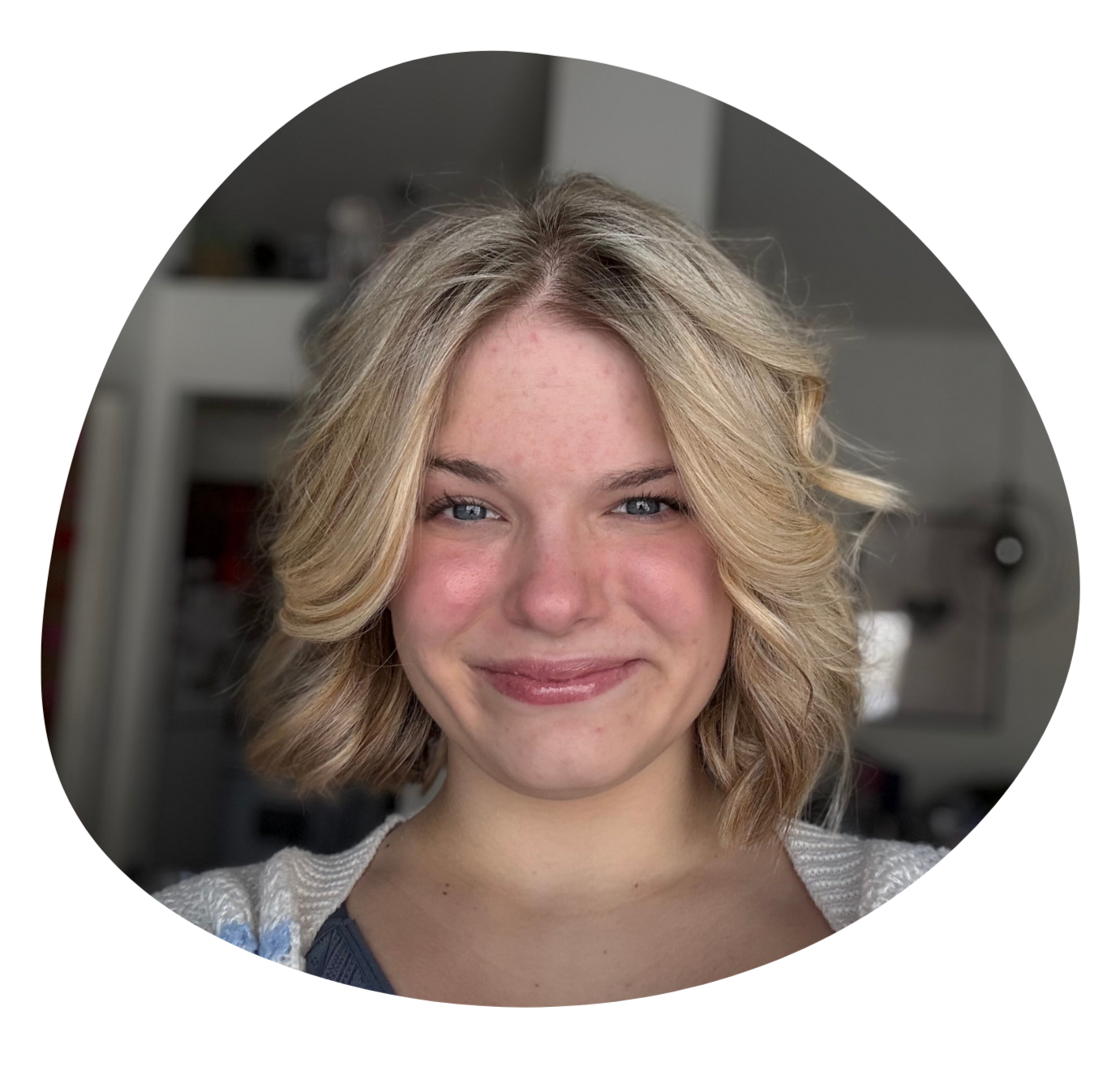 A young woman with blonde, wavy hair and blue eyes smiling.