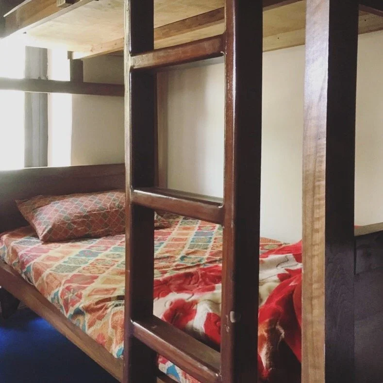 Bunk beds with a colorful quilt and pillow in a room with natural light.