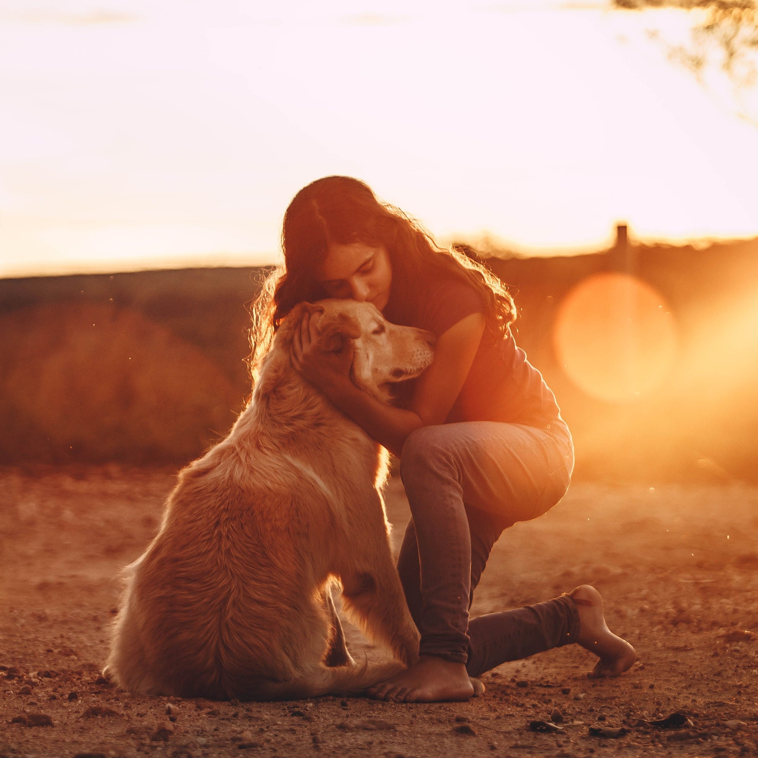 white-jade-animal-and-pet-therapy-woman-kneels-in-warm-sunset-hugging-golden-retriver-companionship