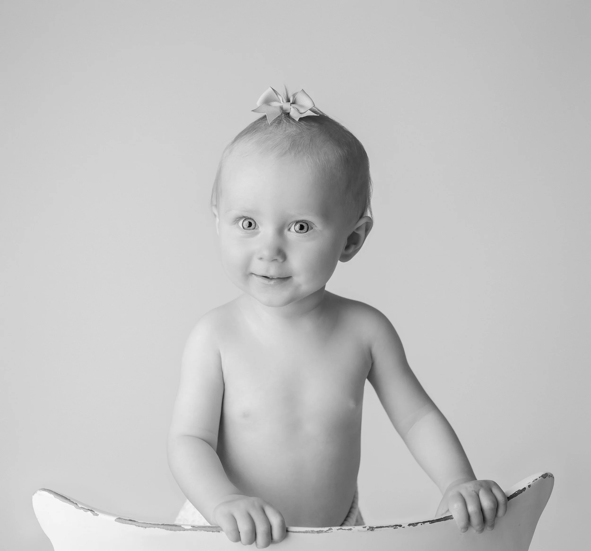 Sjenert barneportal med kort hår og hårbånd, uten klær øverst, holder på en lav platetopp.