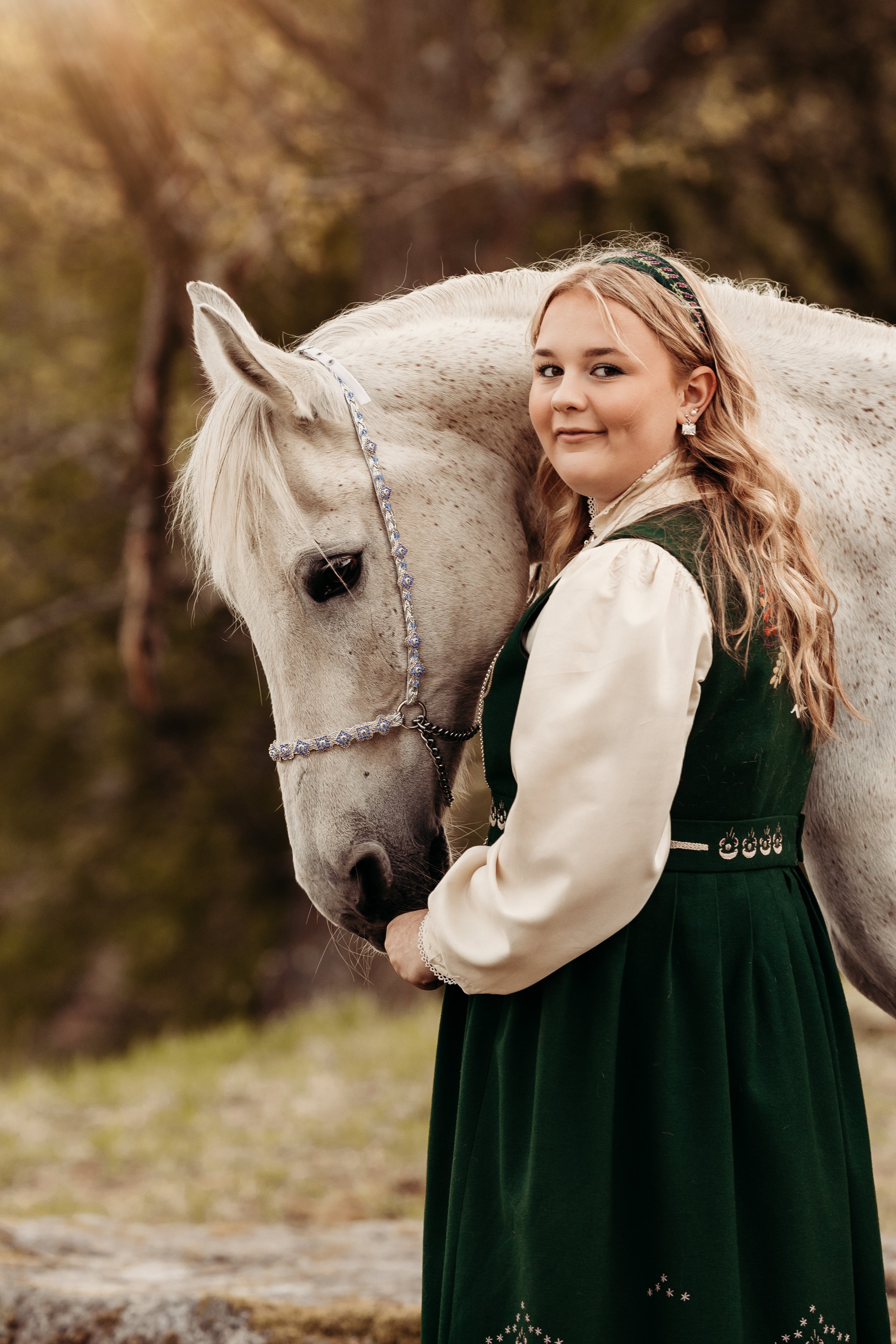 En jente i tradisjonell drakt med en hvit hest.