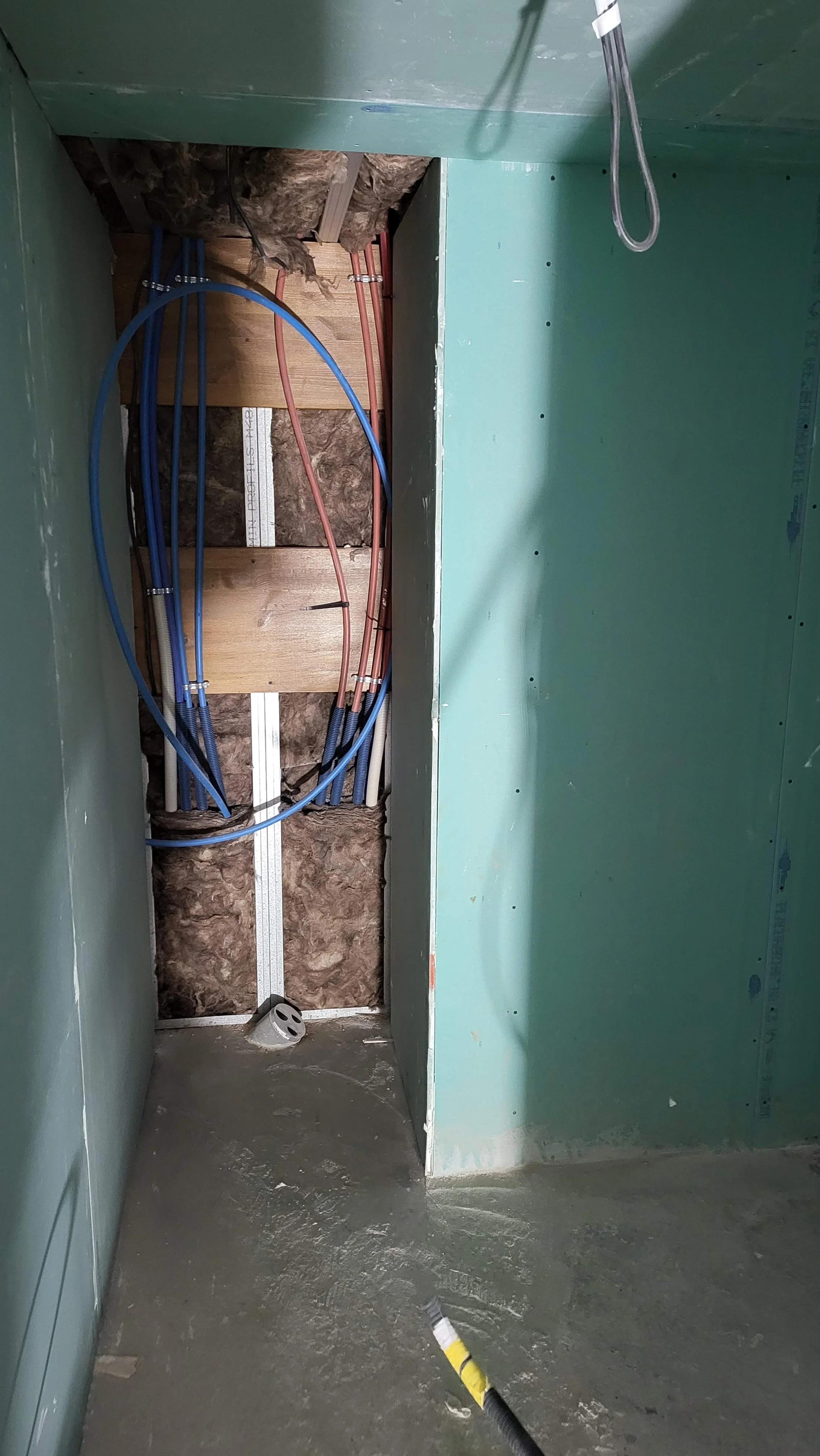 Coffrage en construction avec câblage électrique et plomberie en cours d'installation dans un mur