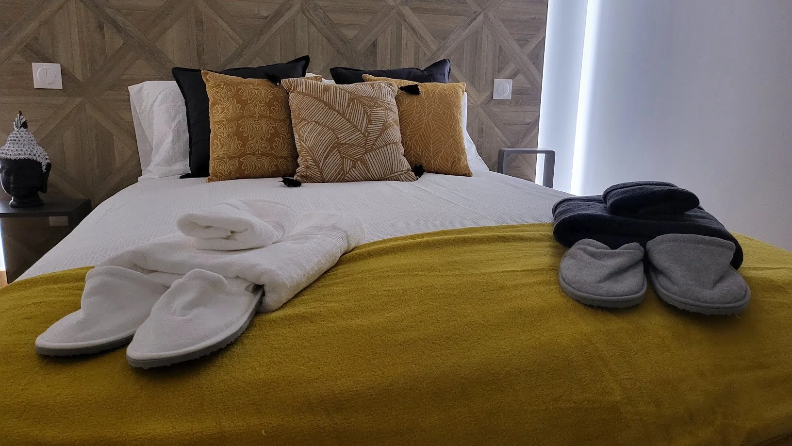 Lits avec des serviettes pliées et des peignoirs, oreillers à motifs et un décor moderne dans une chambre.