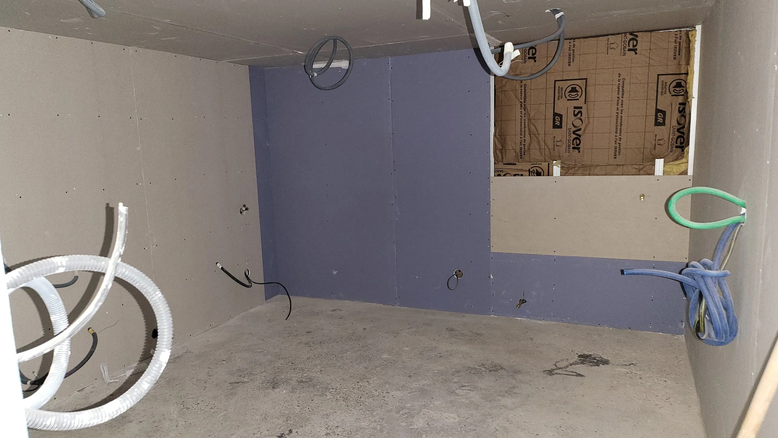 Espace en construction avec câbles électriques et plaques de plâtre sur le mur