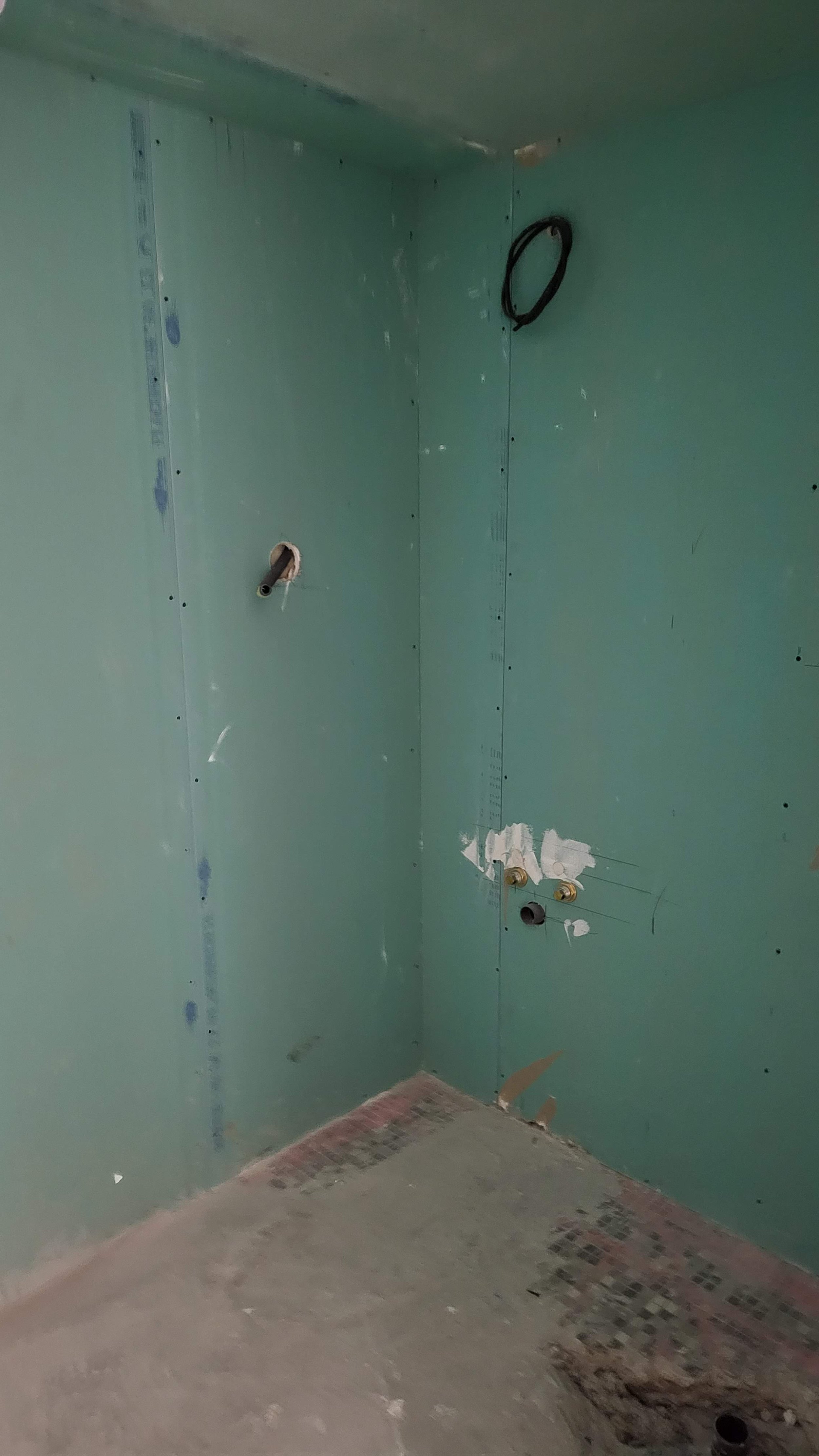 Mur en construction avec conduits et fixer pour installation de plomberie ou d'électricité, sol en béton non fini.