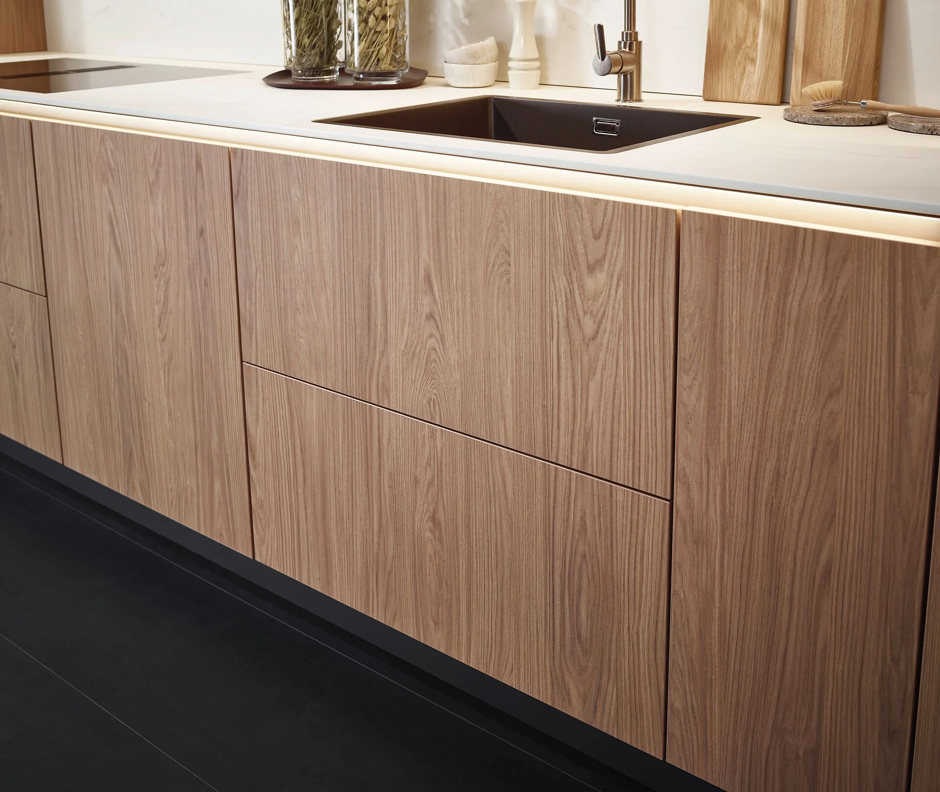 Een keuken met houten kasten, een zwart gootsteen en een witte werkblad.